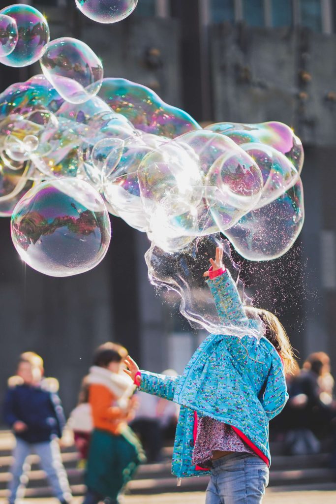 kid playing in a park with a big bubble