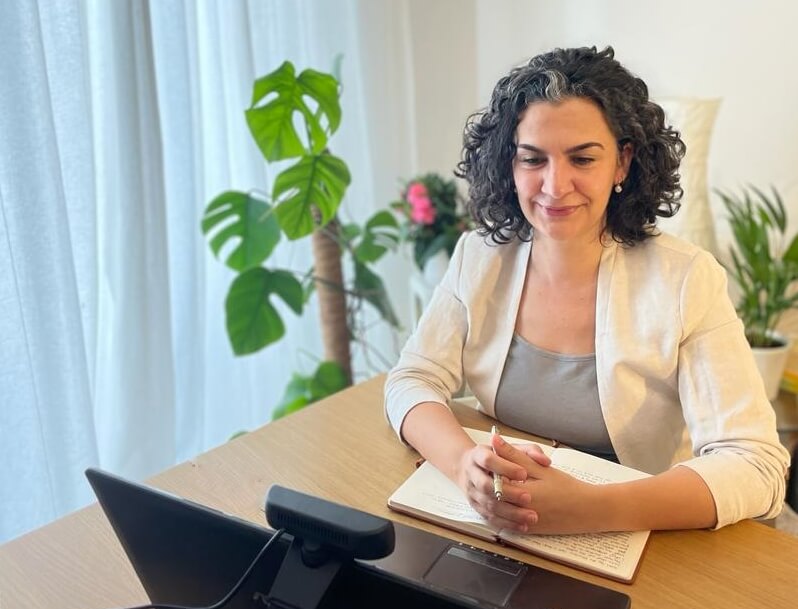 Stefania sitting in front of computer smiling during online session