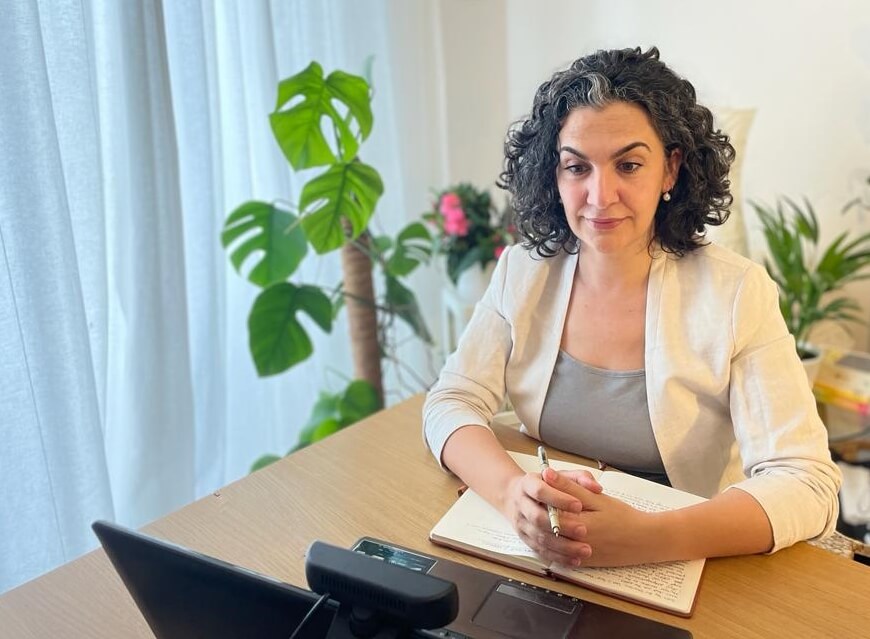 Stefania sitting in front of computer smiling during online session