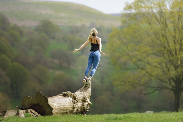 Woman jumping from a trunk with open arms